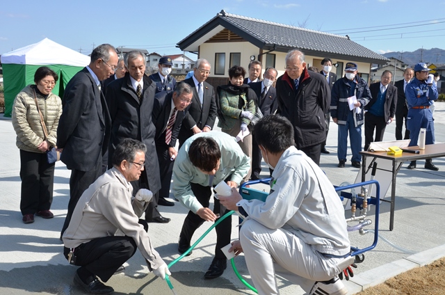 造水機で作られた飲料水を見る参列者